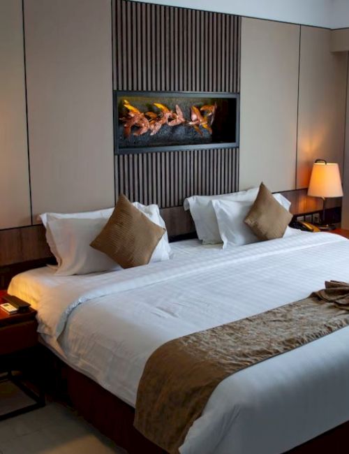 A cozy hotel room with a large bed, two side tables with lamps, wall art, and a window with curtains.