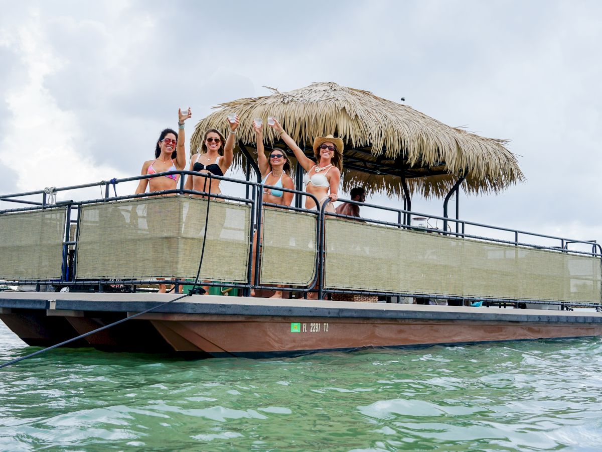 A group of people on a floating barge with a thatched roof, enjoying themselves on the water.