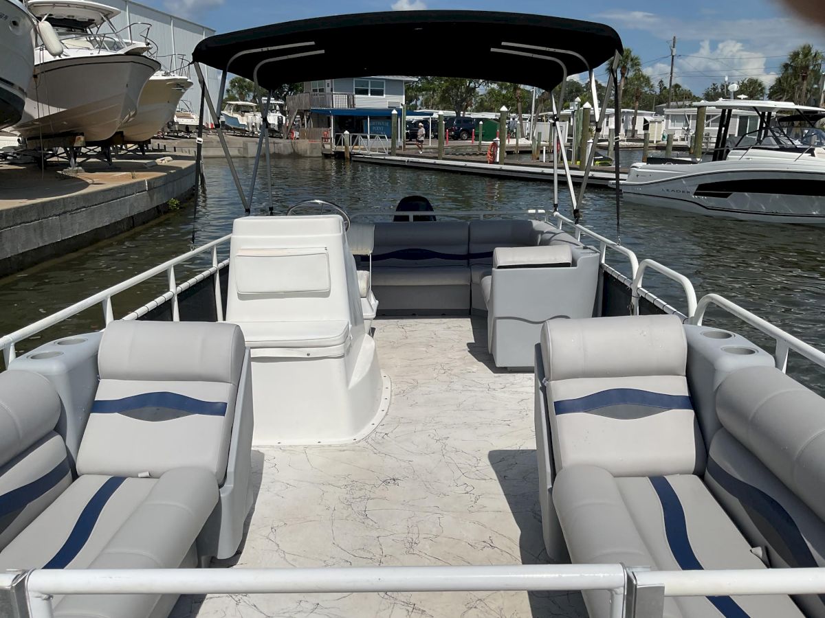 View from a motorboat showing cushioned white-and-blue seats, open helm area, and marina docks with other boats in calm water.